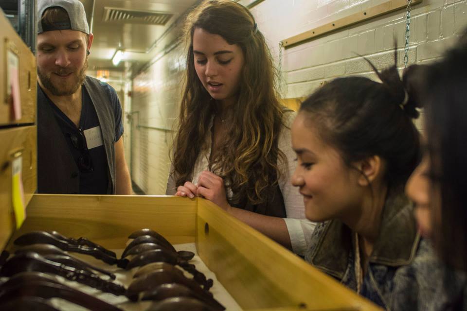 Image depicting Cassie Pontone giving visitors a closer look at some wooden spoons during a tour through CAS Mezzanine storeroom. Selected for use on the homepage of the Philippine Heritage Collections interactive web portal. (c) Field Museum of Natural History - CC BY-NC 4.0