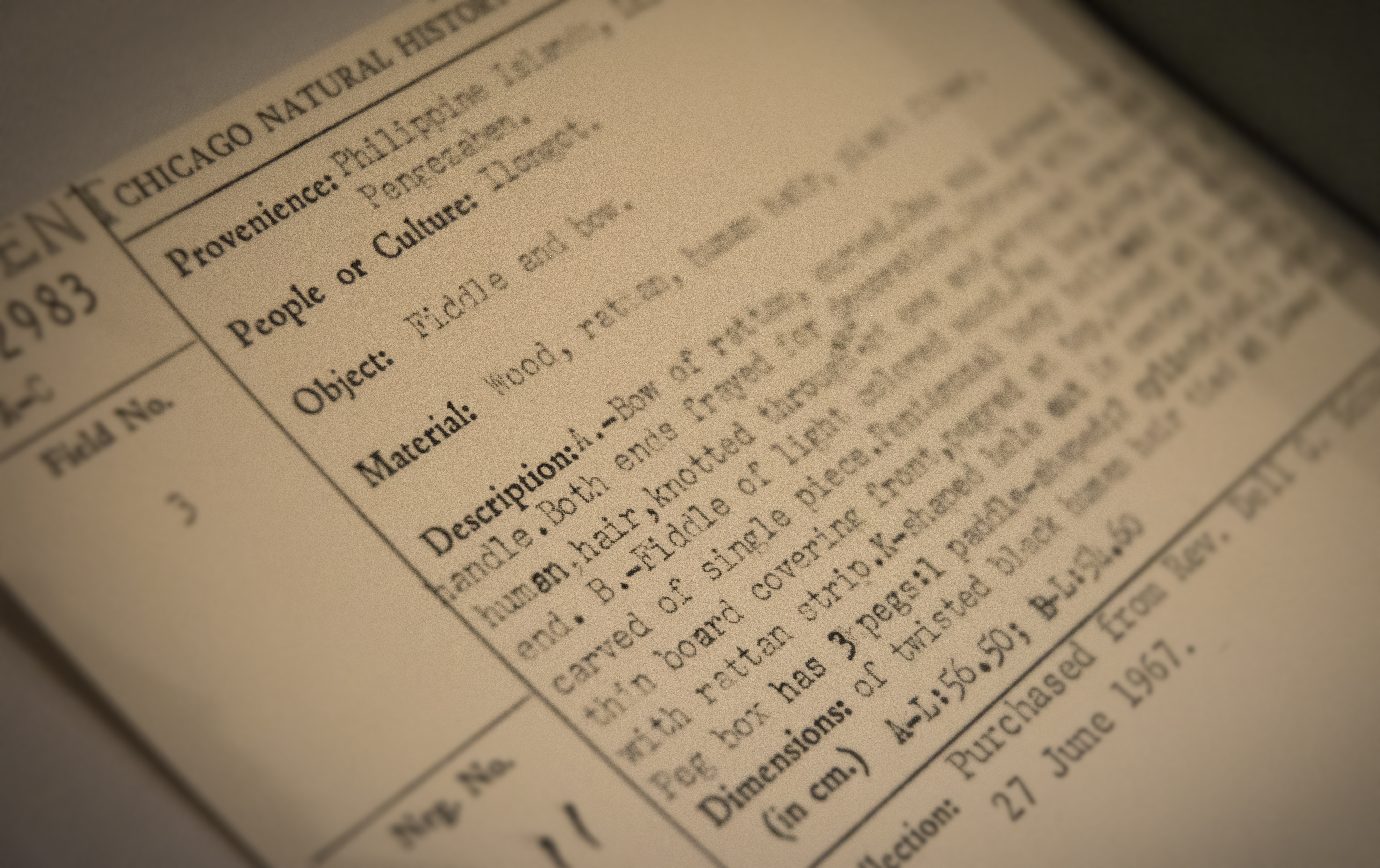 Close up of catalog card for 130213 (fiddle and bow) on artifact display table. (c) Field Museum of Natural History - CC BY-NC 4.0