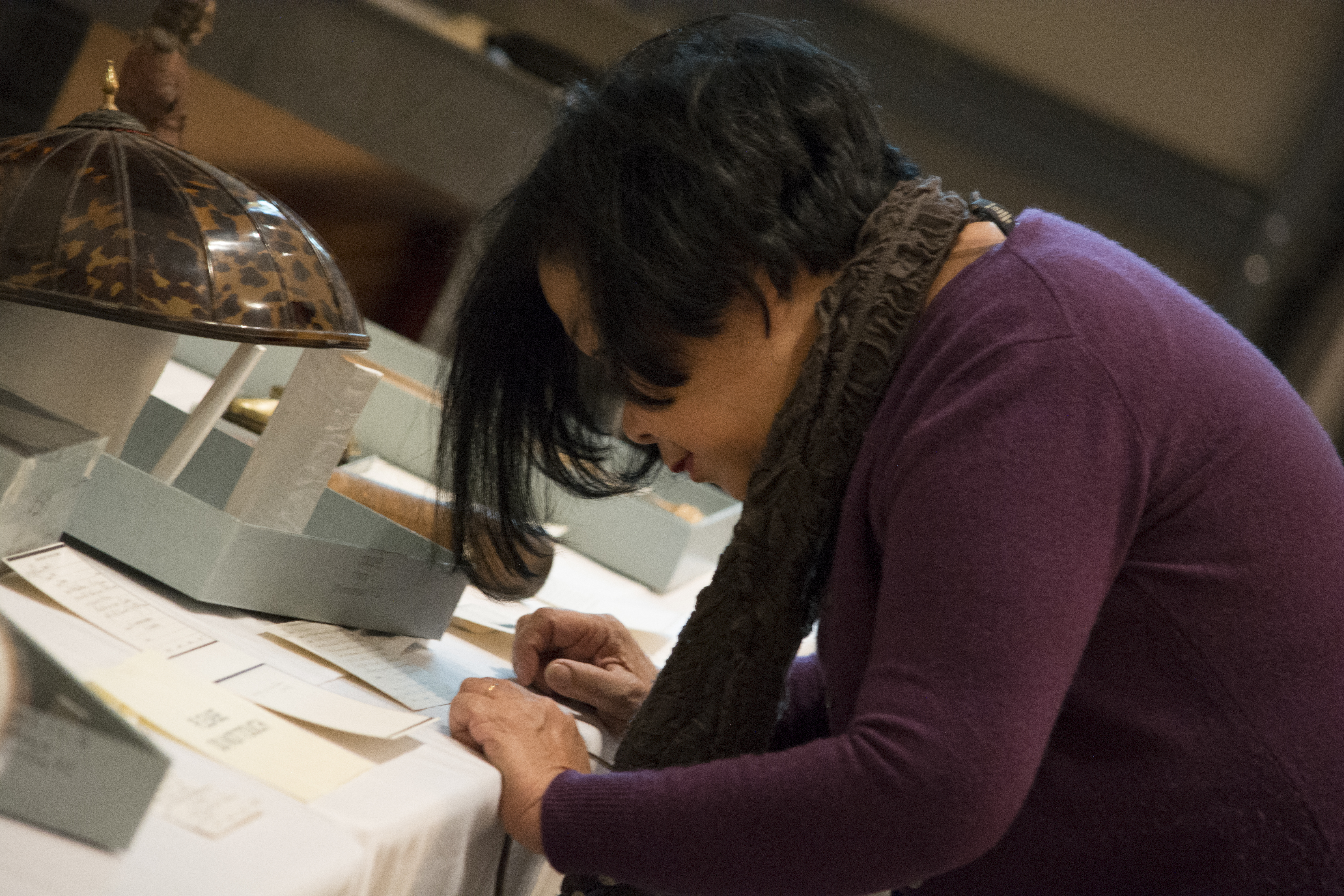 Guest getting a closer look at the catalog card for a man's hat. (c) Field Museum of Natural History - CC BY-NC 4.0