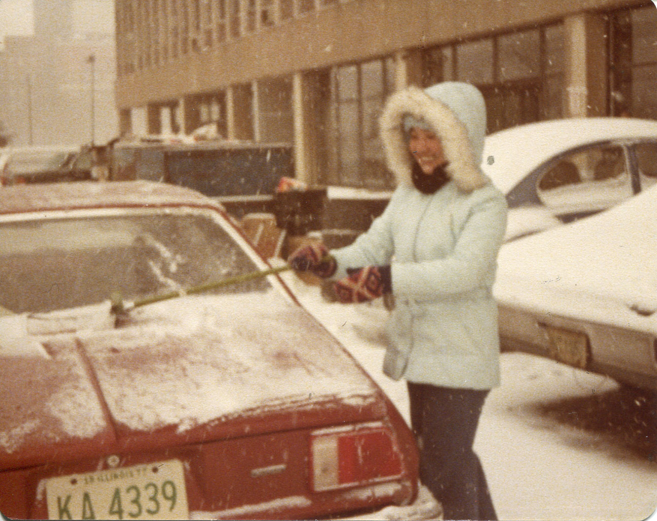 Photo of Etta McKenna, 1977.Taken in Jan 1978 in the parking lot of 1926 W Harrison. First snow in Chicago winter ‘78,Taken by “my friend, Agnes Clement, while cleaning her car.”Pictured: “myself cleaning the car” [One woman in cleaning snow off a car]Notes from Sarah Carlson, in discussion with McKenna: “This reminds me of my first snow in Chicago. I was wearing a parka bought from Woolworth’s on sale. It was a thin parka so one of the first experiences in the cold. Not since I came to Chicago had I felt how cold is‘cold’! Cleaning my friend’s car, a Chevy Monza. Any views, findings, conclusions, or recommendations expressed in this story do not necessarily represent those of the National Endowment for the Humanities. (c) Field Museum of Natural History - CC BY-NC 4.0