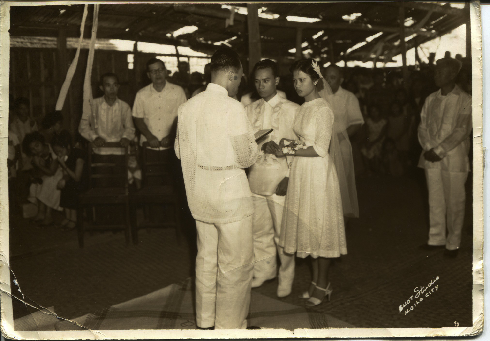 Photo of Arguelles' parents' wedding, 1958.Arguelles acquired it in 2011 after her dad died. The photo was taken on Nasidman Island, Iloilo at Arguelles’ parent’s wedding. The wedding took place in Aglipay Church, which was an Indigenous religion mixed with Catholicism. Text on the photo says: “Buot StudioIloilo City”. Pictured: Pastor, Jose Arguelles (dad “Tay”), Magdalena (mom “Nay”), Pedro B Molina (maternal grandfather, mayor of Ajuy). Arguelles’ mom was an oldest child. She was the first nurse in her family and sent all her siblings to school. Arguelles’dad was a second child and also sent all his siblings to school. Arguelles said her parents coming together is symbolic of the future of the Philippines at that time. Her parent’s generation is still very involved in the Philippines. Hundreds of people like them helpedothers, though they themselves came from nothing. Any views, findings, conclusions, or recommendations expressed in this story do not necessarily represent those of the National Endowment for the Humanities. (c) Field Museum of Natural History - CC BY-NC 4.0