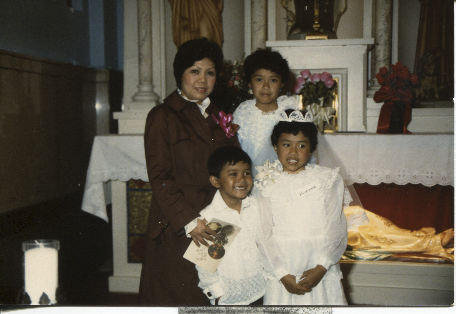 Photo of Tan's family, 1987 Taken in Chicago at Our Lady of Pompeii Church, Lexington. The back of the photo says “Please return to Necitas D. Tan class of 1963”. Pictured: back row L-R: Necitas, daughter Simonette. Back row: son Jason, daughter Vivienne. Tan said the photo, “shows the beginningof my life.” Tan said the photo shows her family and represents the transition from being single to being married with a family in America. Tan’s husband (Cesary Tan) is taking the photo. Tan is an orphan; her father died in WWII. She took an exam and passed it to getinto school. All Tan’s children are grown. Her daughter is married and has two kids in San Diego. Tan’s daughter Simonette is the manager of an investment company. Her daughter Vivienne is a graphic designer. Her son Jason an electronic engineer. Any views, findings, conclusions, or recommendations expressed in this story do not necessarily represent those of the National Endowment for the Humanities. (c) Field Museum of Natural History - CC BY-NC 4.0