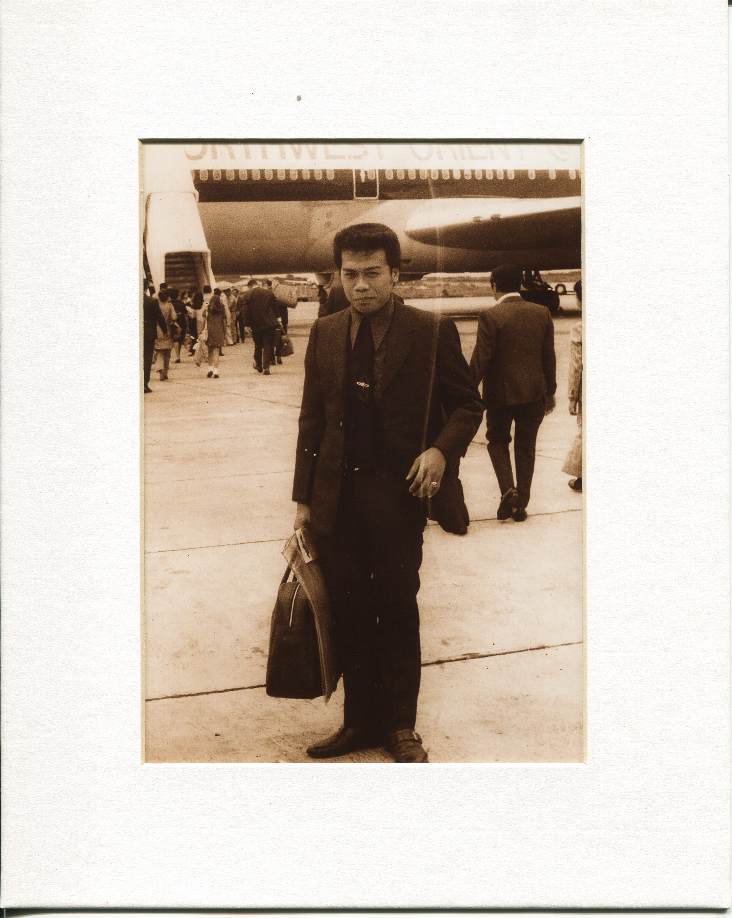 Photo of Virgilio Vergara, Vanessa Vergara's father, June 1972Vergara learned about photo in 2012 from aunt who had the photo hanging on her wall in Solano, Nueva Vizcaya. The photo was taken at the Manila airport and shows Vergara’s father leaving for the US via the Northwest Orient. Pictured: Vergara’s father (Virgilio), “alldressed to the nines”.  Vergara’s paternal grandfather was a tailor at his shop, called Philippines Bazaar, therefore her father had a strong fashion sense. Vergara’s father is wearing a tie and coat and has a small piece of hand-carry luggage (containing his paperworkfor emigration- all he brought with him.) He has a flat top haircut which was “in vogue at the time.” She said he has a nice smile and looks confident but a bit uneasy.  In 1972, Vergara’s father was the oldest of six and as such had a responsibility to help hisfamily. Vergara said he emigrated for financial opportunities. Vergara’s father planned to enter the US at Port of Maine but, at the last minute, it was changed to Chicago. There, Vergara’s father met his future boss and future father-in-law. In 1970, Vergara’s motherwas petitioned by her father, who was Virgilio’s boss. Vergara said she is very proud of how her father worked hard to come to the USA and encouraged his children to get the best education. Vergara wants to keep stories alive as was as heritage. Any views, findings, conclusions, or recommendations expressed in this story do not necessarily represent those of the National Endowment for the Humanities. (c) Field Museum of Natural History - CC BY-NC 4.0