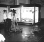 Preparing the educational television program "Down to Earth" with New Trier High School Students and Ernest Roscoe, Raymond Foundation with Mrs. Penny Kneipper, a sixth grade teacher in Wilmette. The Audio Visual [AV] project filmed with movie cameras, microphones and two student moderators.  Charles Knight murals in background, fossil exhibits in Hall 38.