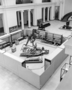 View from 2nd floor down into Stanley Field Hall. Preparators Orville Gilpin and unidentified, in the Gorgosaurus" pen. Preparation progress of the skeleton (now Albertosaurus) and Lambeosaurus.  [see Albertosaurus, Daspletosaurus] Includes laders, carts, 2 skeletons, Carl Akeley bronze Lion Spearing sculptures in background.