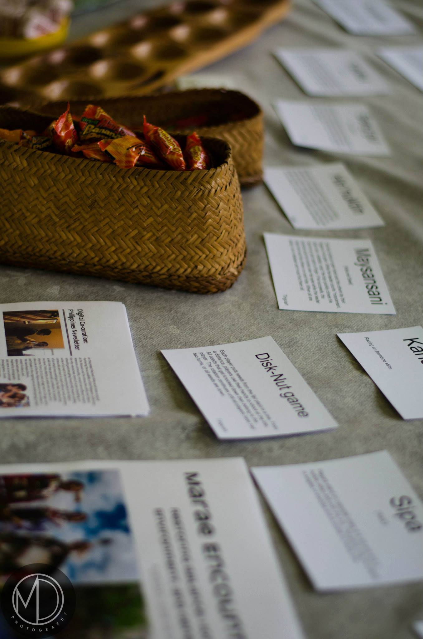 Close up of The Field Museum's table in the Cultural tent, covered with handouts, descriptions of traditional Filipino games, and a basket of candy. 