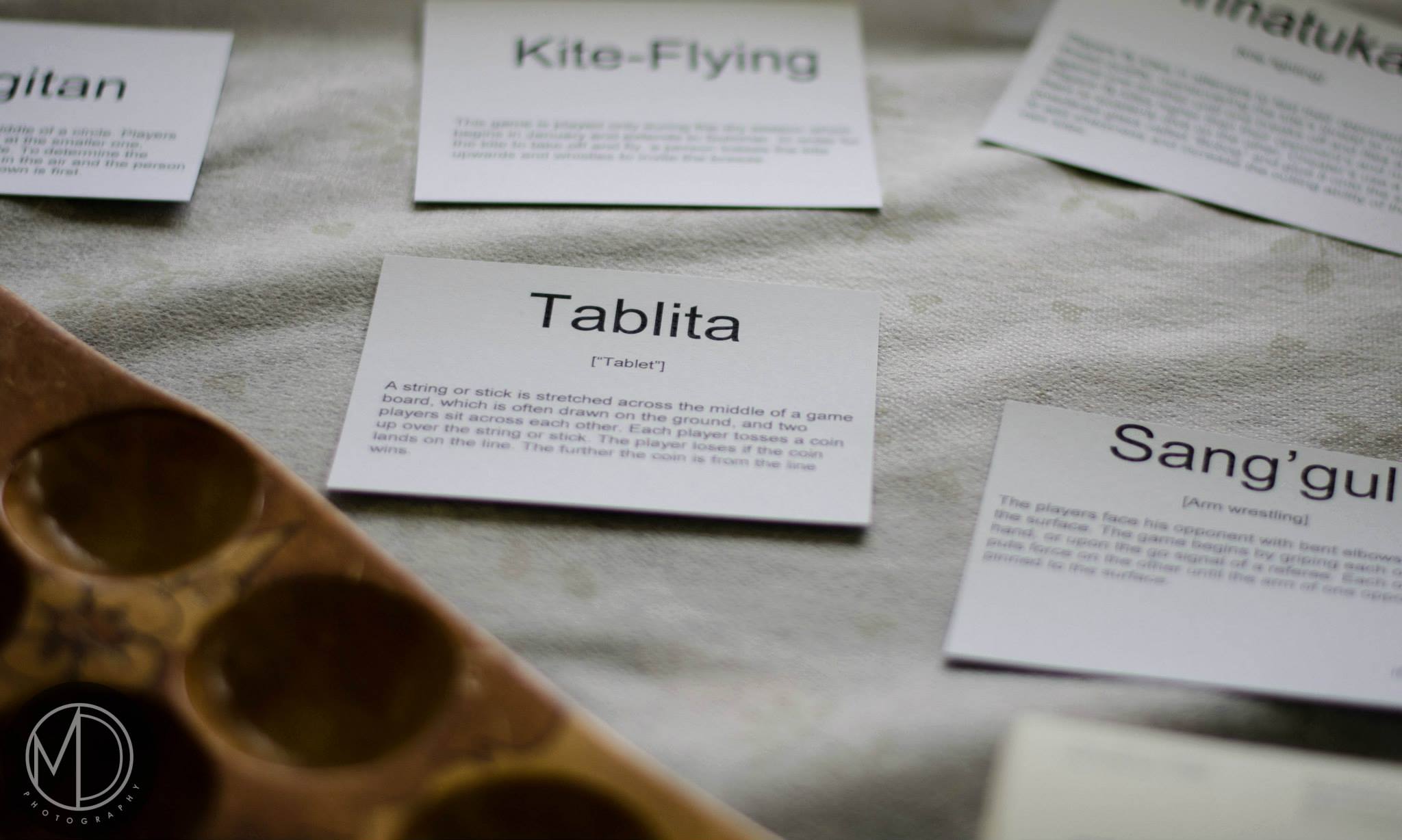 Close up of cards describing traditional Filipino games and sunca board on The Field Museum's table in the Cultural tent. 